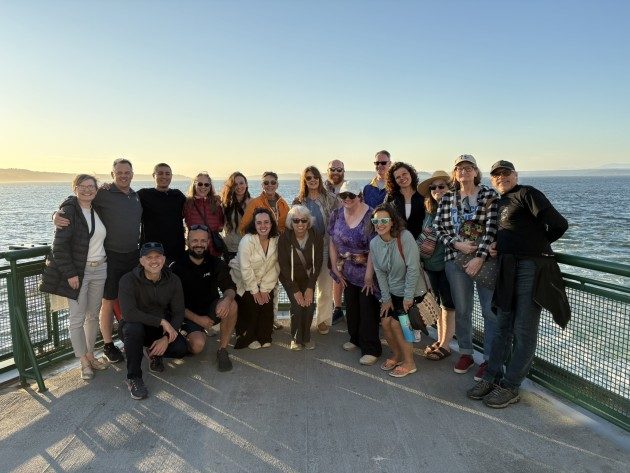 Kata Together participants gathered for a group photo on the ferry deck at golden hour, with the Puget Sound behind them.
